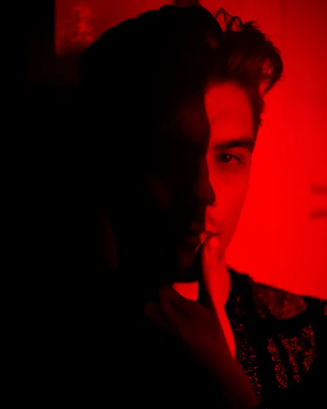A man half-lit by deep red light, looking off to the side